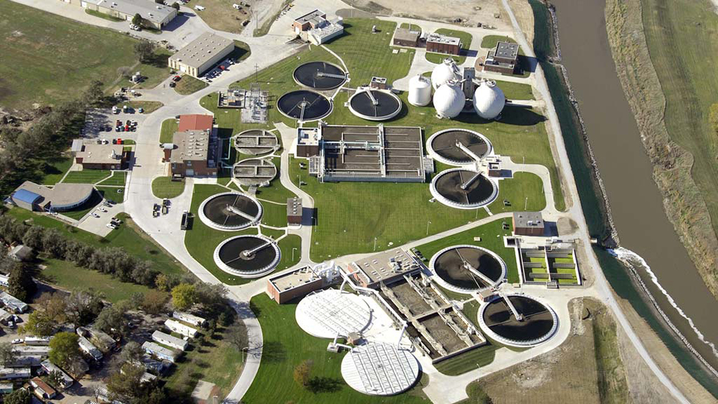 Aerial view of a large campus with many buildings, round treatment tanks, and walkways between.