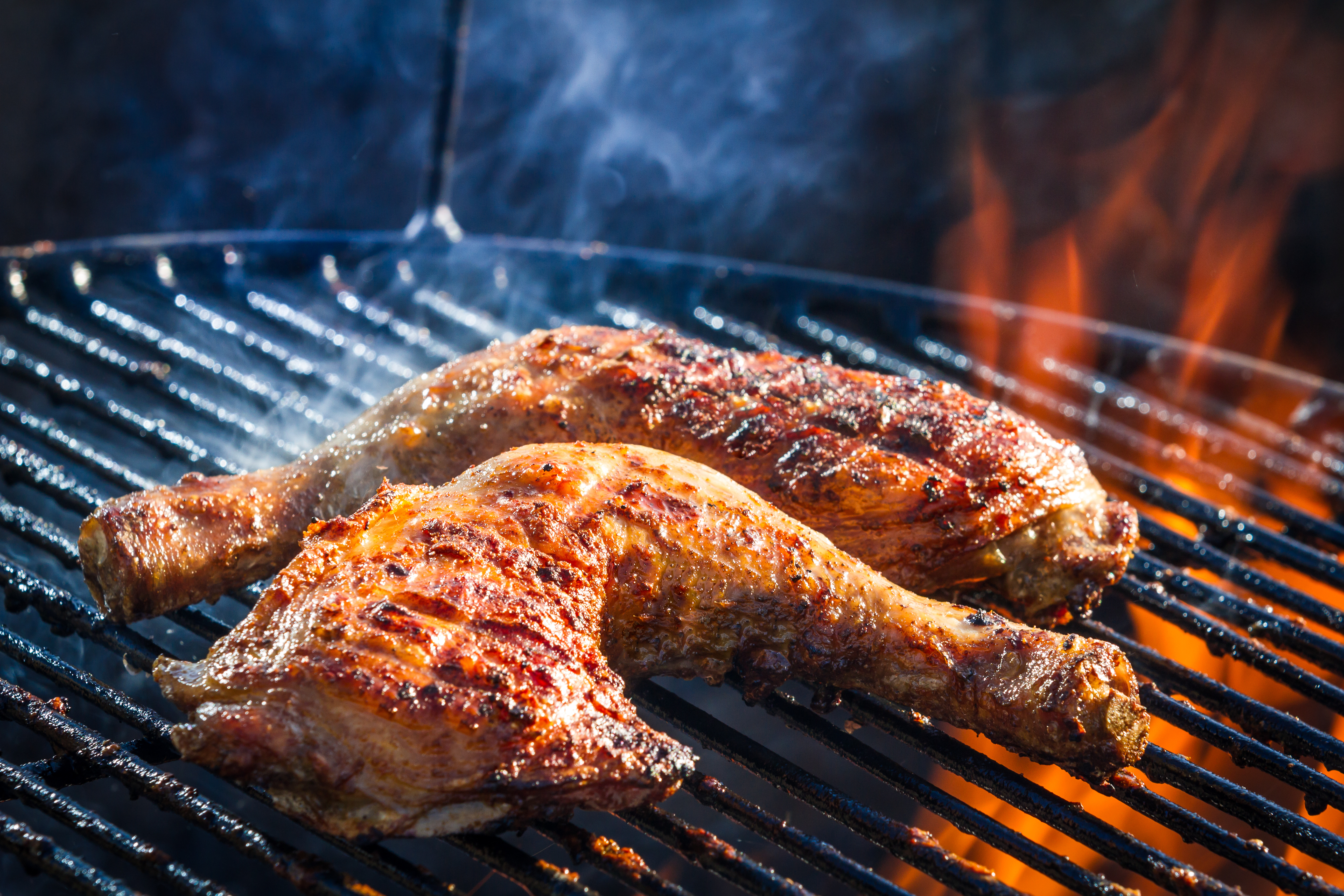 Chicken is grilling over a charcoal fire.