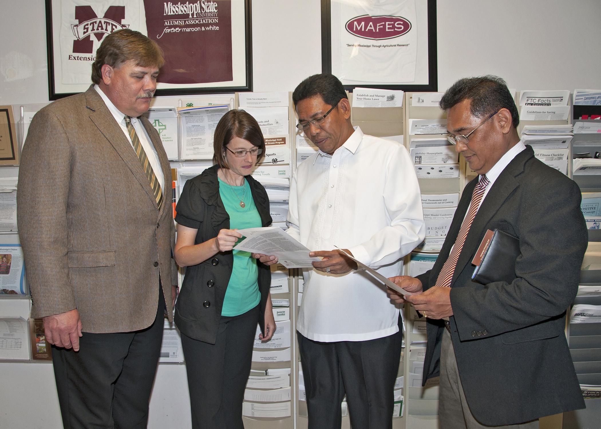 Mississippi State University Extension Service Director Gary Jackson and Oktibbeha County Extension Coordinator Julie White review some of the many publications available through Extension with Edilberto DeLuna and Asterio Saliot, members of an agricultural delegation from the Philippines, visiting the county office on May 28, 2013. (Photo by MSU Ag Communications/Kat Lawrence)