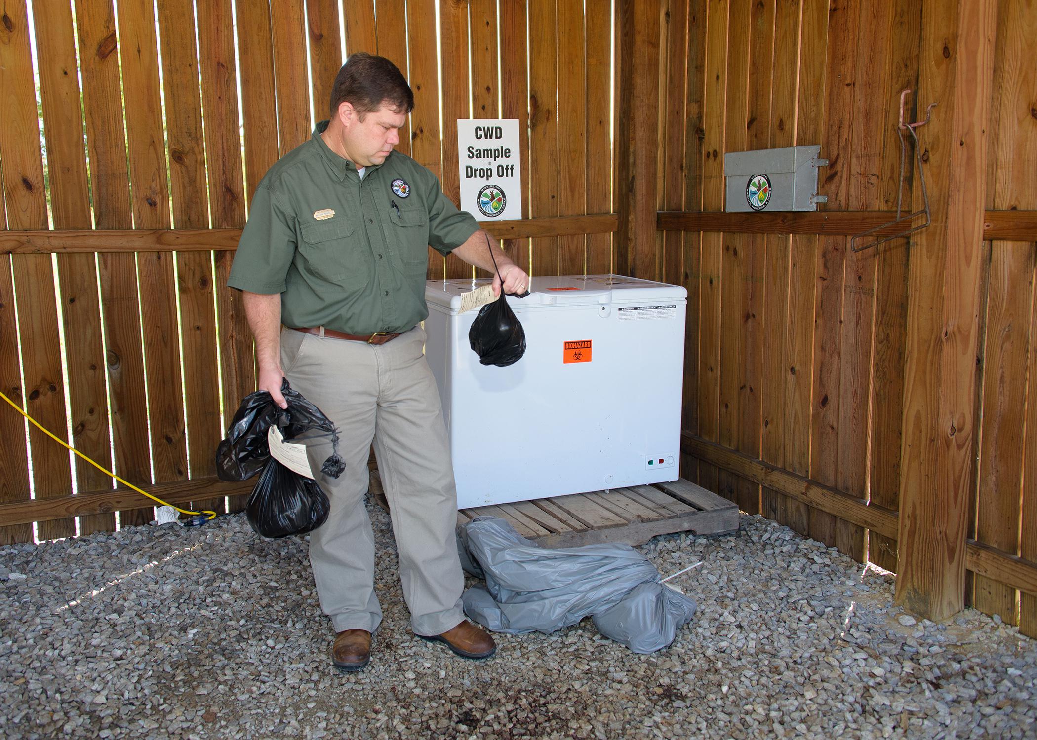 A man holds items in an open shed.