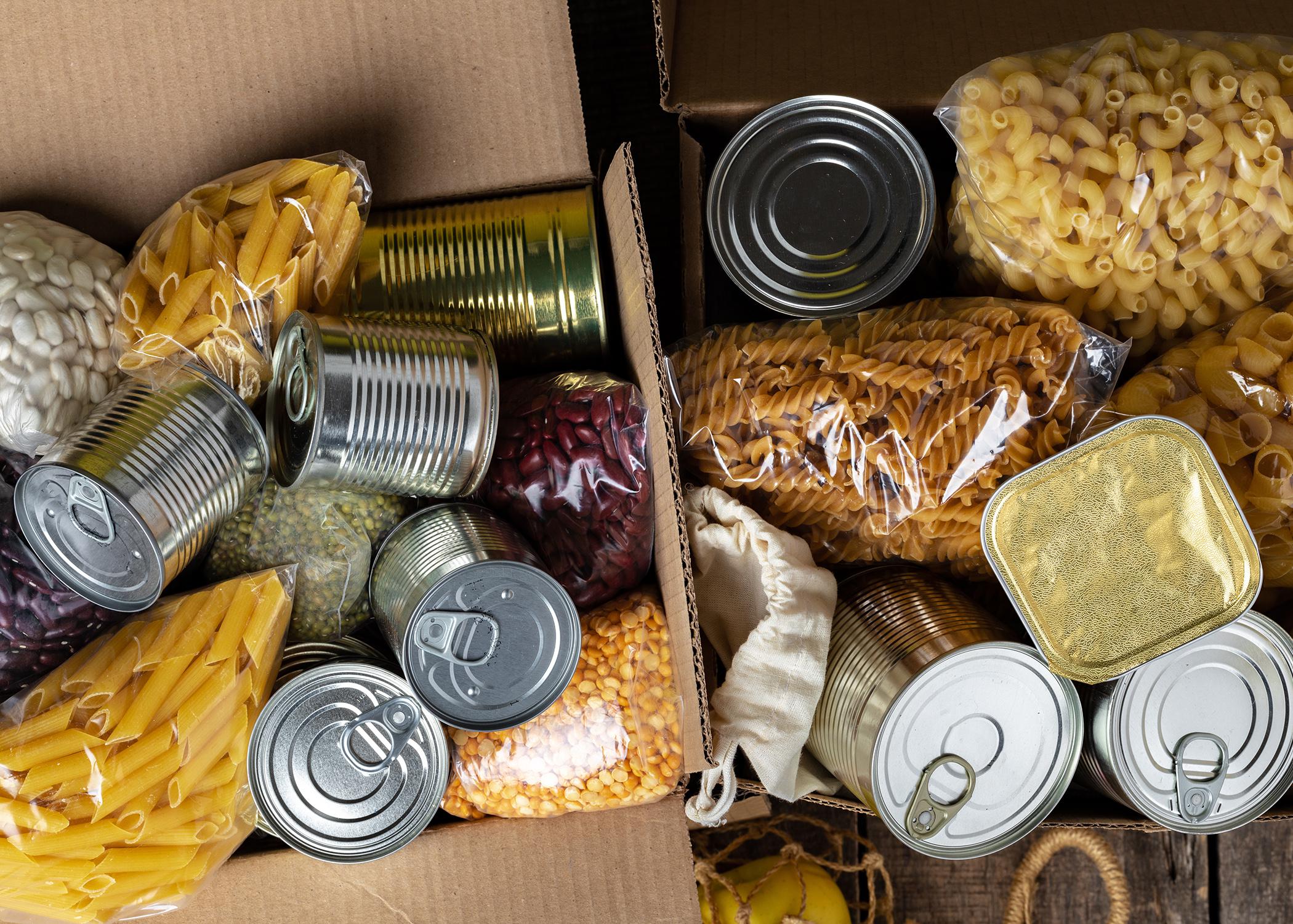 A box of food to donate, including beans, pasta, and canned goods.