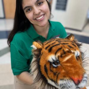 A woman wearing a green polo hugging a plush tiger.