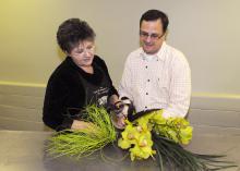 Mississippi State University florist manager Lynette McDougal and horticulture professor Jim DelPrince create a unique wedding arrangement of cymbidium orchids, lily grass, bear grass and feathers. (Photo by Kat Lawrence)