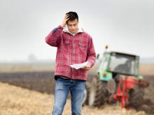 Man on a farm holding a baseball cap.