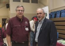 Two men stand together in a meeting space.