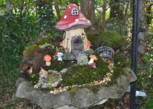 A red mushroom house is the focal point of a fairy village.