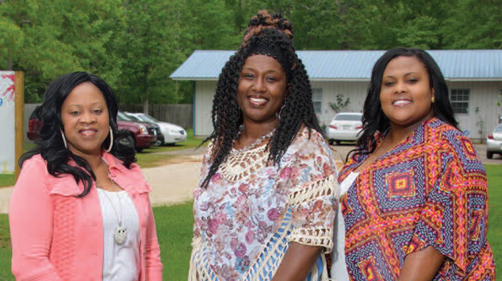 Three smiling women stand next to each other.