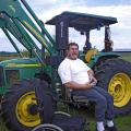 Chris Bell sits next to his tractor that has been equipped with a lift device and hand controls so he can operation it from his wheelchair. (Photo by Emily Knight/Mississippi State University Extension Service) See larger view.