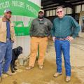 Three men and a black dog stand in front of a sign that reads "Dantzler Phillips Pilkinton."