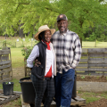 A smiling couple standing next to each other in a garden.