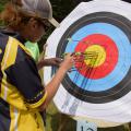 A 4-H’er wearing sunglasses tallies arrows in a colorful paper archery target.