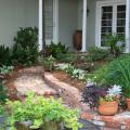 A curving brick walkway lined with plants leads up to a porch.