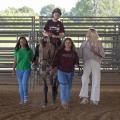 Boy riding a horse surrounded by three people.