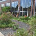 A gravel trail cuts through a garden in front of a building.