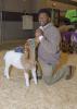 A young man kneels next to his goat at the Dixie National Sale of Junior Champions.