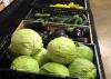 Light green lettuce, dark purple eggplant and cucumbers sit on black shelves.